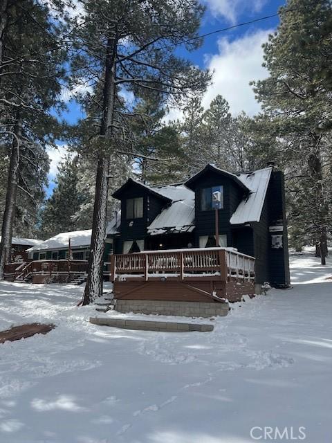 snow covered back of property with a deck