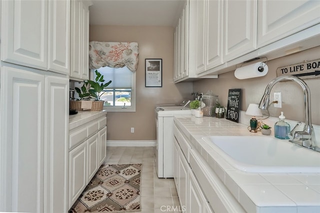 washroom featuring washing machine and dryer, light tile patterned flooring, sink, and cabinets