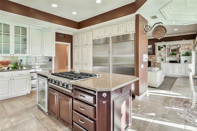 kitchen with dark brown cabinets, wine cooler, a kitchen island, decorative backsplash, and stainless steel appliances