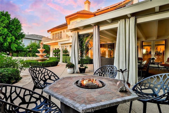 patio terrace at dusk with a balcony and an outdoor fire pit