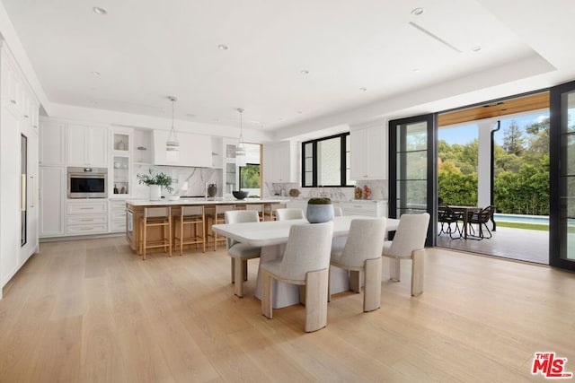 dining space featuring light hardwood / wood-style floors and a tray ceiling