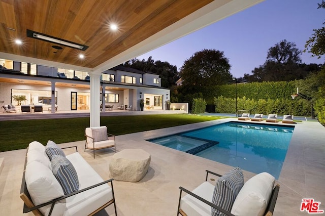 pool at dusk with a patio area, an outdoor hangout area, an in ground hot tub, and a yard