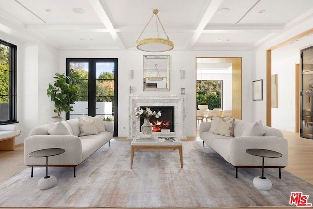 living room featuring light hardwood / wood-style flooring, a healthy amount of sunlight, and coffered ceiling