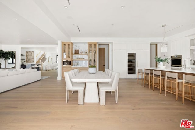 dining room with light hardwood / wood-style floors, wine cooler, and sink