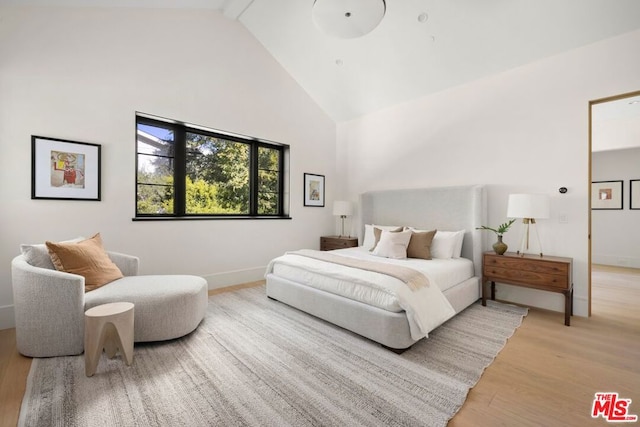 bedroom with beamed ceiling, light hardwood / wood-style floors, and high vaulted ceiling