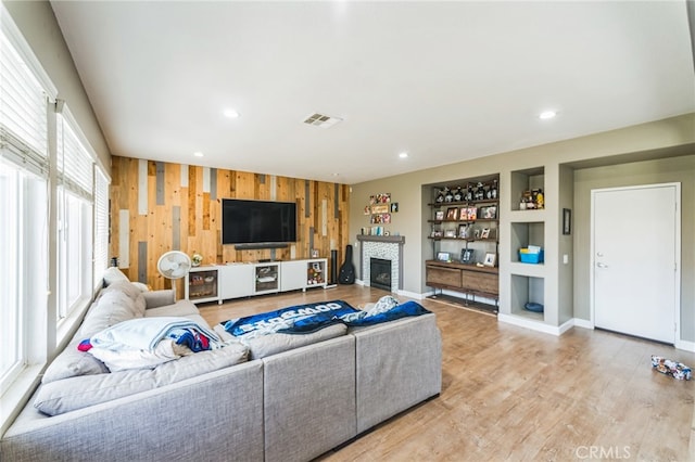 living room with wood walls, light hardwood / wood-style floors, and a fireplace