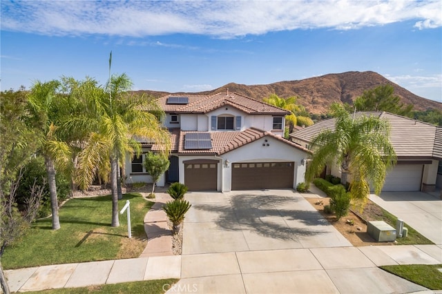 mediterranean / spanish house with a mountain view, a garage, and a front lawn