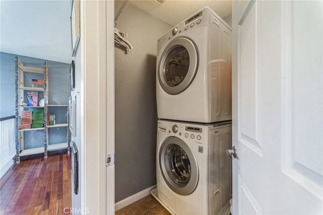 laundry area with stacked washer / drying machine and dark hardwood / wood-style floors