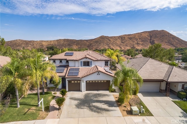 view of front of house with a front yard, a mountain view, a garage, and solar panels