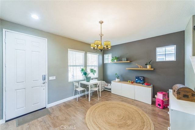 interior space with an inviting chandelier, light wood-type flooring, and a healthy amount of sunlight