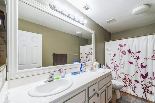 bathroom featuring a shower with curtain, vanity, toilet, and a textured ceiling