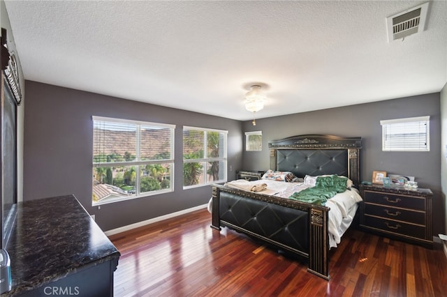 bedroom with multiple windows, dark wood-type flooring, and a textured ceiling