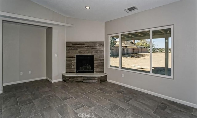 unfurnished living room with lofted ceiling and a tiled fireplace