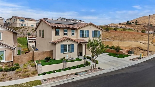 mediterranean / spanish home featuring fence, driveway, solar panels, stucco siding, and a tile roof