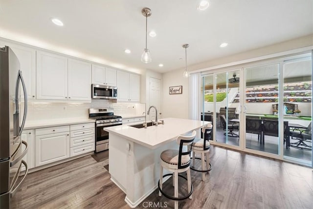 kitchen featuring white cabinets, sink, light wood-type flooring, appliances with stainless steel finishes, and decorative light fixtures