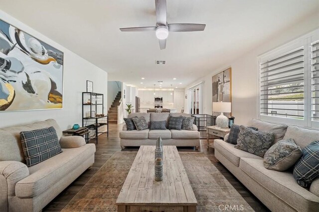 living room featuring ceiling fan and dark wood-type flooring