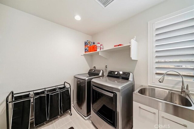 laundry room with cabinets, independent washer and dryer, light tile patterned floors, and sink