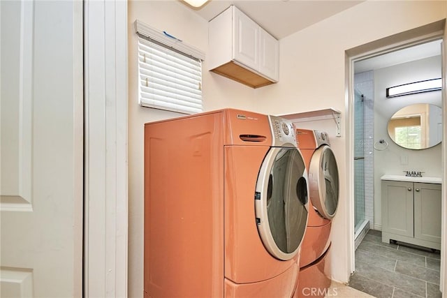 washroom with cabinets, light tile patterned flooring, a wealth of natural light, and washing machine and clothes dryer