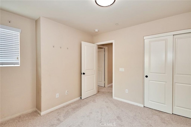 unfurnished bedroom featuring light carpet and a closet