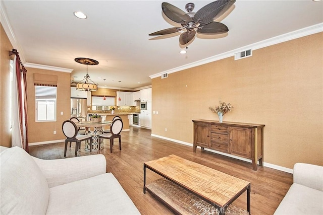 living room featuring crown molding, hardwood / wood-style floors, and ceiling fan