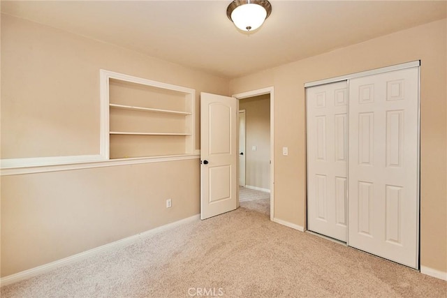 unfurnished bedroom with a closet and light colored carpet