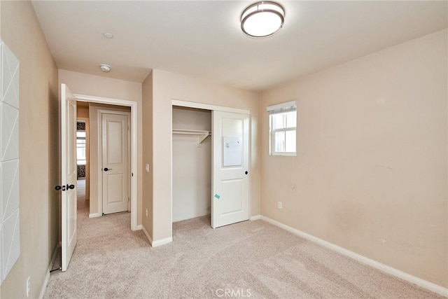 unfurnished bedroom with light carpet and a closet