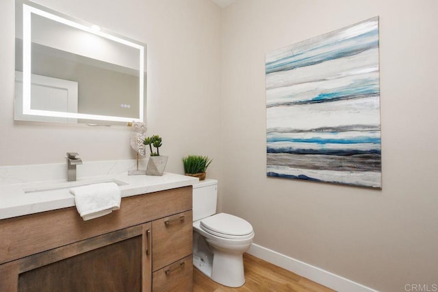 bathroom with toilet, vanity, and hardwood / wood-style flooring