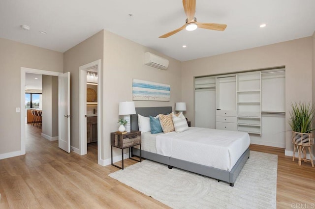 bedroom featuring ensuite bath, ceiling fan, light hardwood / wood-style flooring, a wall mounted AC, and a closet