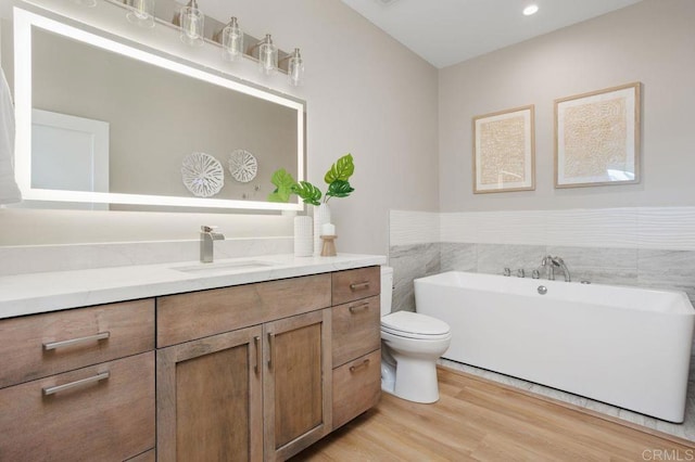 bathroom with wood-type flooring, vanity, toilet, and a bathtub