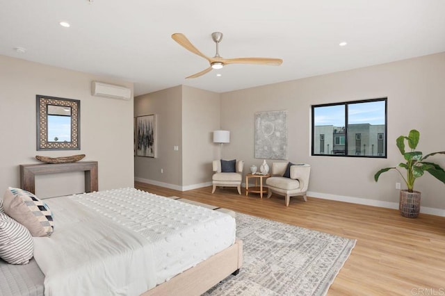 bedroom with light hardwood / wood-style floors, a wall unit AC, and ceiling fan