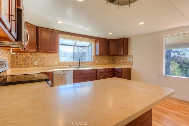 kitchen with appliances with stainless steel finishes, a wealth of natural light, a sink, and tasteful backsplash