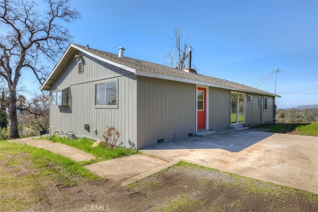 exterior space with a patio, a shingled roof, and crawl space