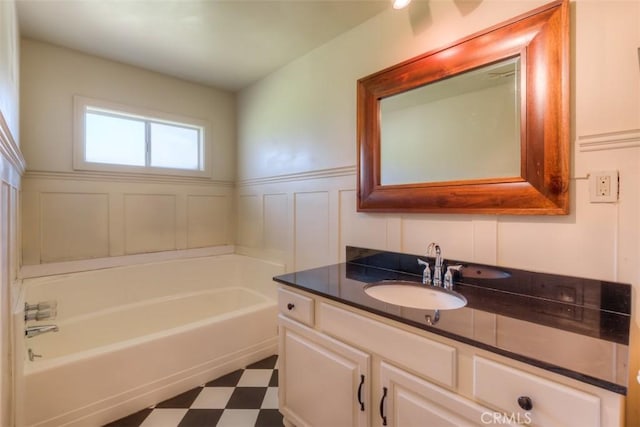 full bathroom with a tub to relax in, a wainscoted wall, tile patterned floors, vanity, and a decorative wall