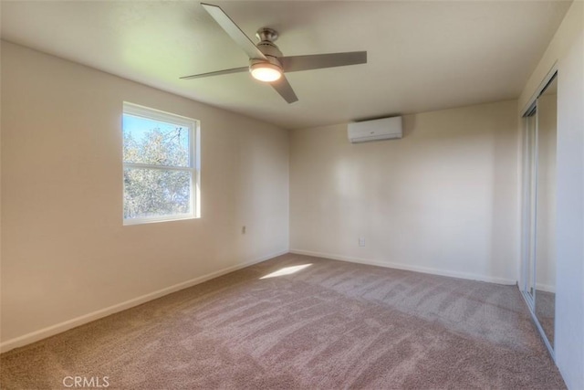 spare room with a wall mounted AC, carpet, a ceiling fan, and baseboards