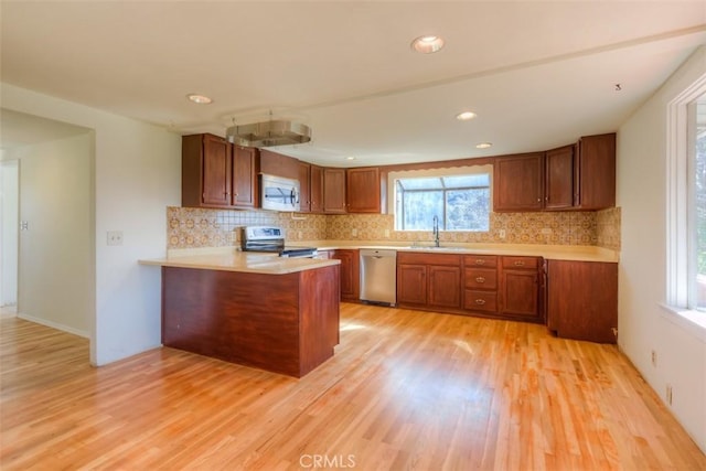 kitchen with backsplash, stainless steel appliances, a sink, and brown cabinetry