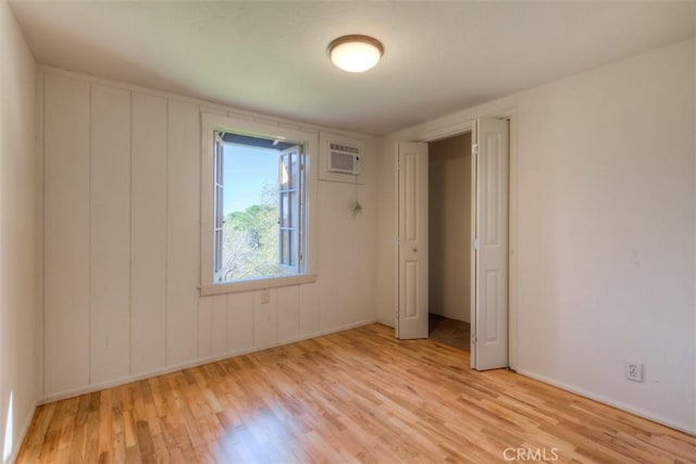 unfurnished bedroom featuring a wall unit AC and light wood-style floors