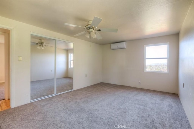 unfurnished bedroom featuring ceiling fan, a closet, a wall mounted air conditioner, and light colored carpet