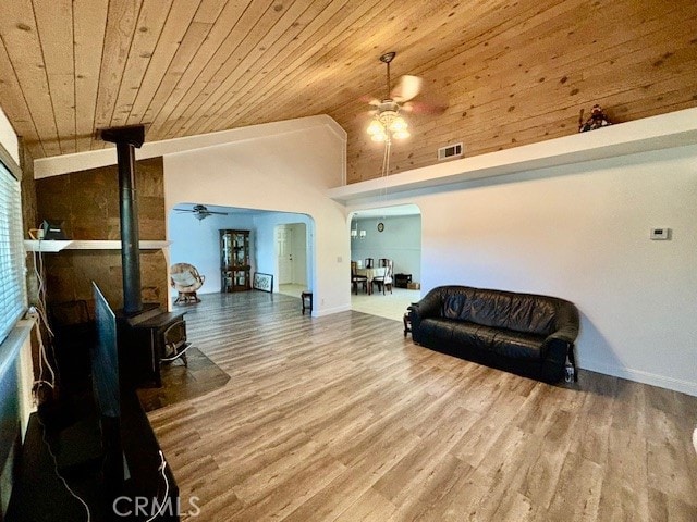 living area featuring high vaulted ceiling, a wood stove, hardwood / wood-style flooring, and wooden ceiling