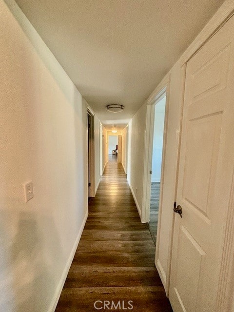 corridor with a textured ceiling and dark hardwood / wood-style floors