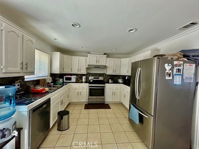 kitchen featuring sink, white cabinets, stainless steel appliances, light tile patterned floors, and ornamental molding