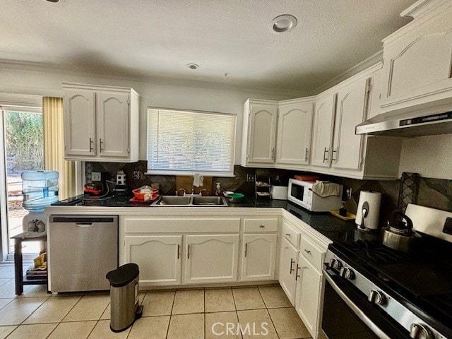 kitchen featuring appliances with stainless steel finishes, white cabinets, light tile patterned floors, exhaust hood, and sink