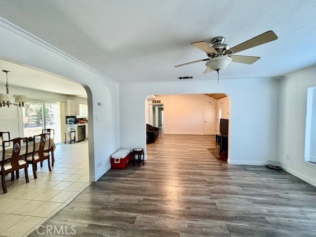 empty room featuring ceiling fan with notable chandelier, hardwood / wood-style flooring, and crown molding