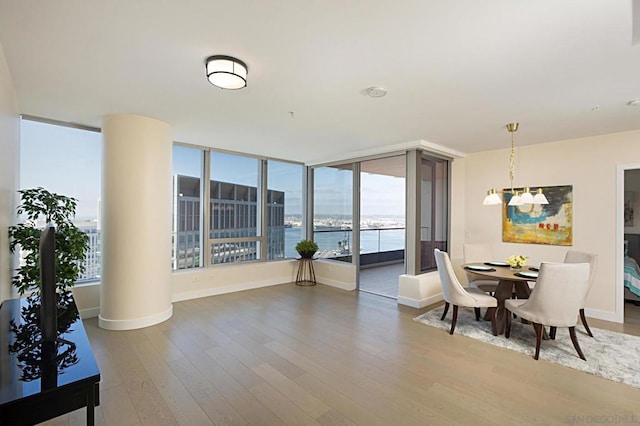 dining area with wood-type flooring, a water view, and an inviting chandelier