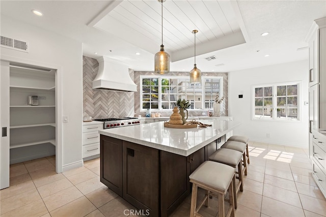 kitchen with backsplash, custom range hood, light tile patterned floors, pendant lighting, and white cabinets