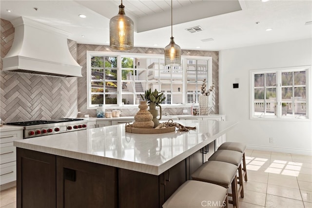 kitchen with white cabinets, hanging light fixtures, decorative backsplash, custom range hood, and dark brown cabinetry