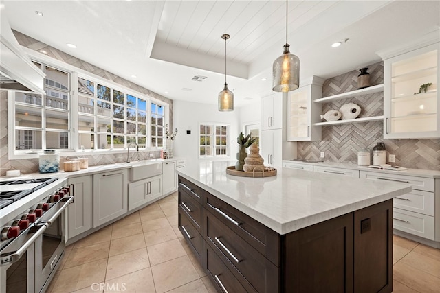 kitchen featuring dark brown cabinetry, sink, hanging light fixtures, premium stove, and custom range hood