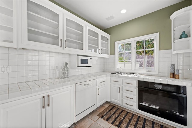 kitchen with white cabinetry, tile counters, white appliances, decorative backsplash, and light tile patterned floors