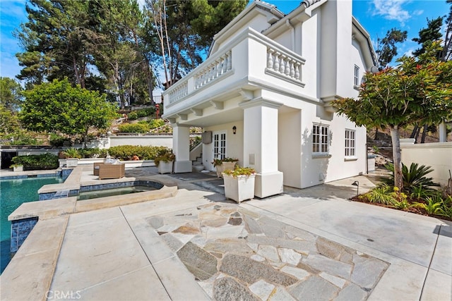 exterior space with a swimming pool with hot tub, a patio, and a balcony