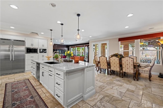 kitchen with a kitchen island with sink, white cabinetry, sink, and stainless steel appliances