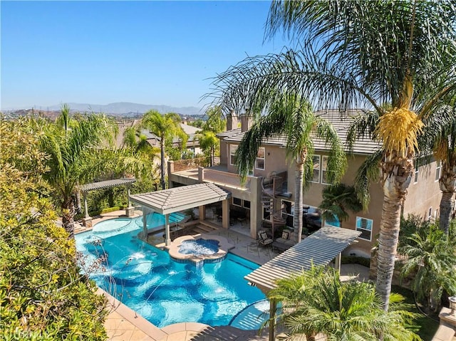 view of swimming pool with an in ground hot tub, a mountain view, and a patio area